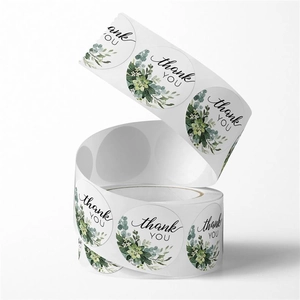 Macro detail of round floral thank you stickers roll with green leaf design on white