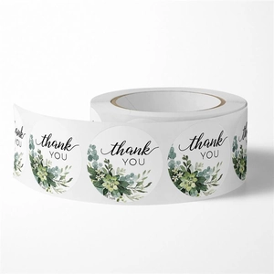 Close-up of round white thank you stickers with green succulent patterns on a roll