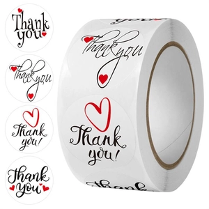 Detail view of round white Thank You stickers with red hearts in a bulk roll