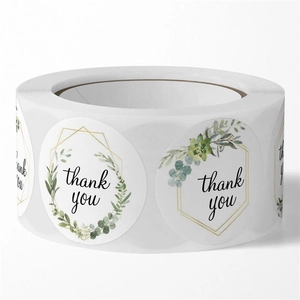 Macro detail of round floral thank you stickers with gold lines on a roll for packaging