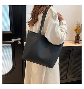 Grand sac cabas en cuir noir porté par un mannequin sur un élégant manteau blanc long