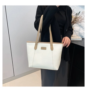 Detail view of a white tote bag with beige leather trim and a Fashion leather label