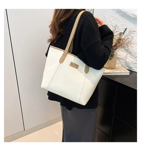 Detail of white tote bag with khaki strap and fashion logo patch for commute