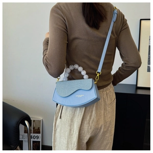 Détail du sac boîte bleu clair avec poignée en perles blanches et bandoulière réglable