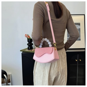 Détail du sac bandoulière rose géométrique avec poignée en perles et rabat texturé