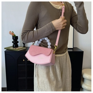 Détail du sac bandoulière rose en cuir PU avec poignée à billes marbrées et sangle réglable