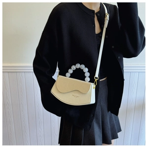 Détail du sac à rabat beige avec bord ondulé, texture tissée et poignée en perles