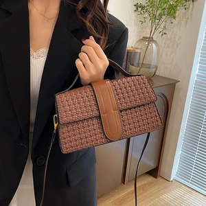 Brown woven texture handbag with crossbody strap shown held in a cozy home setting