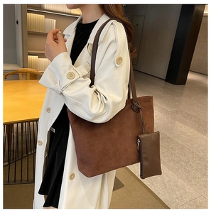 Detail of brown suede tote bag with matching zippered pouch on a stylish model