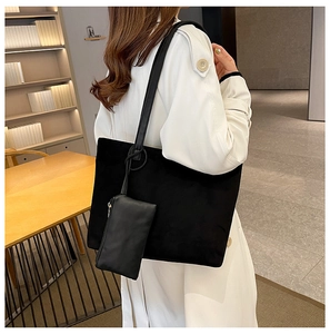 Detail of black suede tote bag with matching zippered pouch on white trench coat