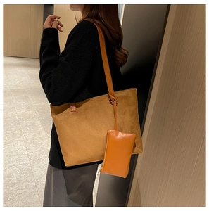 Brown suede tote bag shown on shoulder featuring matching small zipper pouch detail