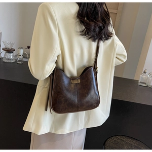 Détail d'un sac seau vintage marron foncé avec texture mate et fermoir magnétique en métal