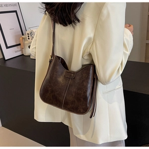 Vue détaillée du sac hobo vintage marron foncé porté avec une veste blazer beige chic