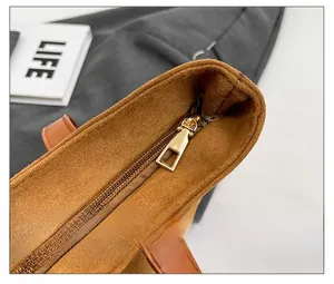 Detail of smooth gold zipper closure on the brown suede tote bag with matte finish