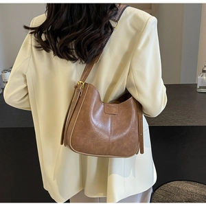 Détail du sac seau hobo marron vintage avec une large bandoulière à motifs géométriques