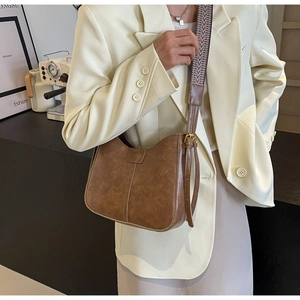 Détail du sac seau vintage marron en similicuir avec large bandoulière géométrique