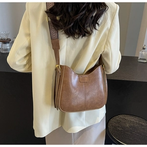 Sac seau vintage en cuir marron avec large bandoulière à motifs sur un mannequin femme
