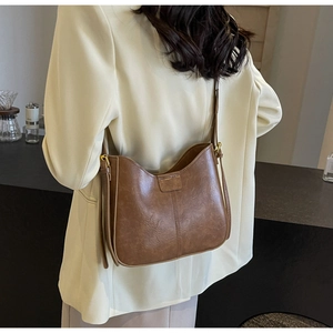 Gros plan d'un sac seau rétro en cuir marron sur mannequin avec texture mate et coutures fines