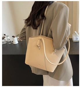 Detail of beige lychee leather tote bag featuring stylish knotted handle and textured finish