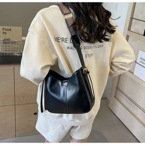 Détail du sac seau noir semi-circulaire avec large bandoulière ethnique et boucle dorée