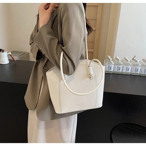 Close-up of white lychee leather bucket bag with elegant round shoulder straps