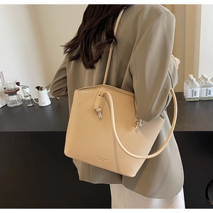Detail of beige lychee pattern leather tote bag worn with casual office style outfit