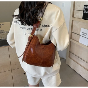 Sac seau demi-lune marron avec texture cuir rétro et bandoulière tissée rayée