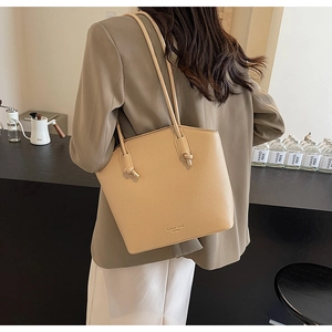 Close-up of beige lychee texture tote bag with knotted straps and gold hardware detail