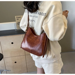 Sac hobo vintage marron avec large bandoulière porté par un mannequin en intérieur