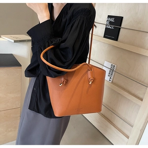 Detail of caramel brown bucket bag with lychee texture and stylish knotted handle
