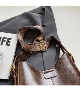 Détail d'un sac seau vintage marron avec bandoulière tissée sur un blazer gris