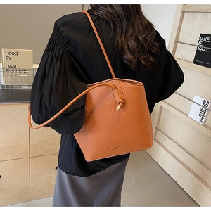 Close-up of orange lychee grain leather bucket bag showing soft texture and minimal strap