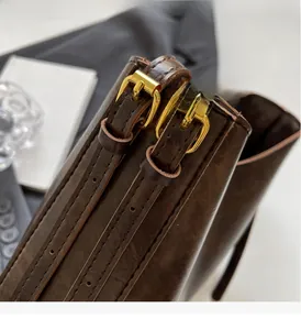 Détail du sac seau en cuir marron rétro avec boucles dorées et coutures précises