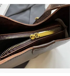 Détail du zip en métal doré lisse et du cuir marron foncé sur un sac seau élégant