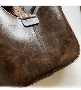 Gros plan d'un sac seau rétro marron en cuir texturé avec large bandoulière tissée