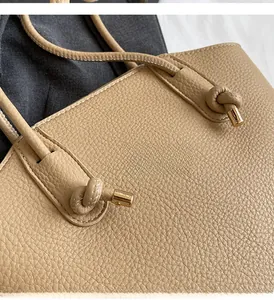 Detail of khaki lychee grain leather bucket bag featuring buckled strap and gold hardware