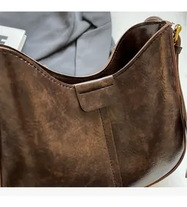 Détail de la texture en cuir plissé marron foncé et des coutures de qualité du sac à main