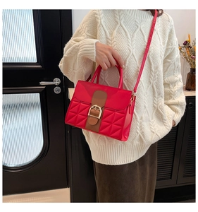 Détail du sac bandoulière rouge matelassé avec textures triangulaires et boucle dorée