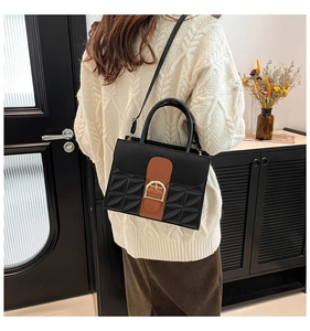 Sac à main chic bicolore avec côtés matelassés et boucle fer à cheval porté par mannequin