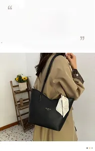 Detail of black pebbled leather tote with gold logo and decorative silk scarf accent