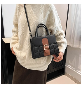 Detail einer Vintage-Handtasche in Schwarz mit goldener Hufeisenschnalle und Steppung