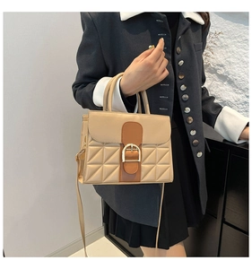 Détail du sac bandoulière en cuir matelassé beige avec bordure brune et boucle dorée