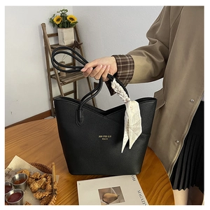 Detail of black pebbled leather tote bag with floral silk scarf wrapped on handles