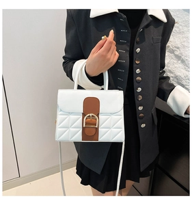 Détail d'un sac à main blanc matelassé avec bandoulière marron et boucle dorée