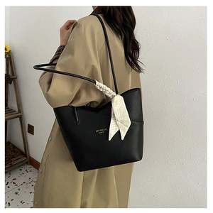 Detail of black pebbled leather tote bag with elegant silk scarf on the shoulder strap