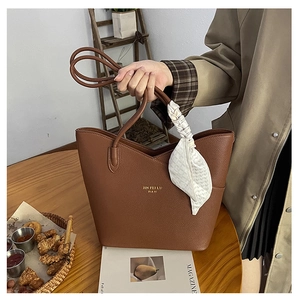 Close-up of brown litchi pattern leather tote bag with stylish silk scarf and gold logo