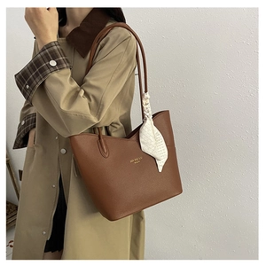 Detail of brown litchi pattern leather tote bag with elegant silk scarf on handle