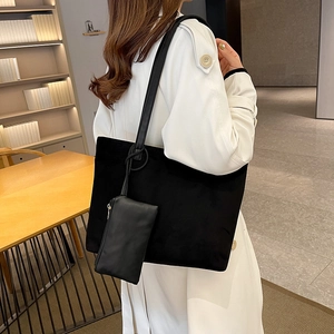 Large black suede tote bag with matching pouch shown worn over the shoulder by a model