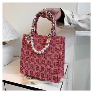 Detail van de rode bruiloft tote bag met Xi-patronen en parelketting handvat
