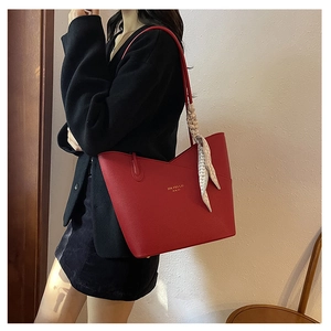 Detail of red pebbled leather tote with gold logo and decorative geometric silk scarf